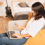 sideways-woman-holding-credit-card-using-her-laptop_23-2148304814