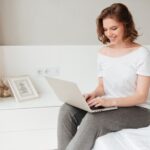 young-cheerful-lady-sitting-indoors-using-laptop-computer_171337-13255